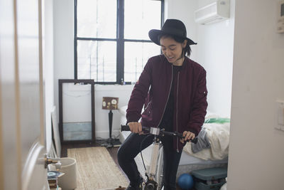 A young woman with a bicycle in a bedroom