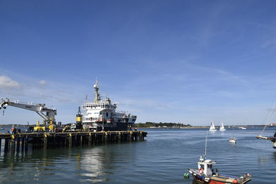 View of commercial dock by sea against blue sky