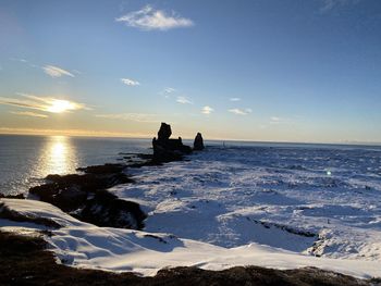 Scenic view of sea and rocks against sky during sunset