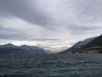 Scenic view of lake garda and snowcapped mountains against cloudy sky