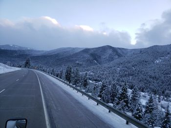 Road by mountains against sky during winter