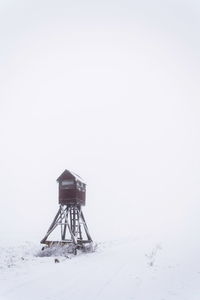 Traditional windmill on snow covered field against sky