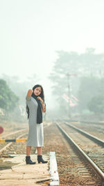 Full length of woman standing on railroad track against sky