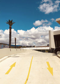 Road sign by palm trees on beach against sky