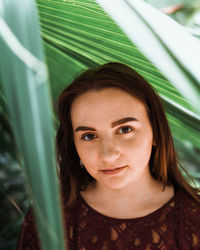 Portrait of smiling young woman by plant