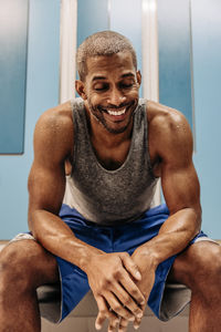 Happy male athlete with eyes closed sitting in locker room