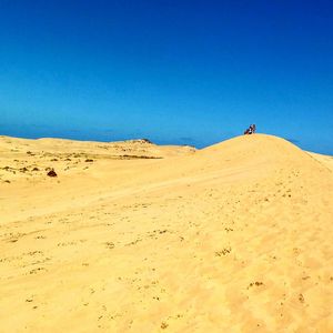 Low angle view of desert against clear blue sky