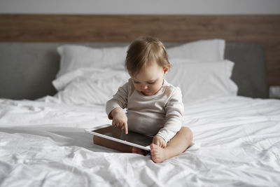 Cute boy using digital tablet while lying on bed at home