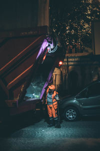 Man standing on illuminated street at night