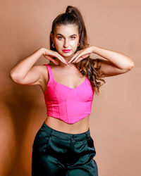 Portrait of young woman standing against yellow background
