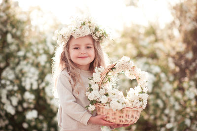 Portrait of cute girl holding flowers standing at park