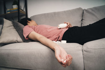 Midsection of woman resting on sofa at home