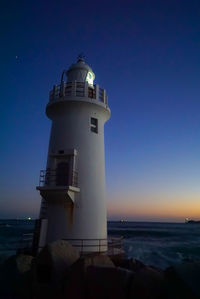 Lighthouse by sea against sky at night