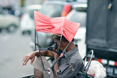 Man holding umbrella on street in city