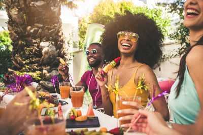 Happy friends with food and drink sitting outdoors