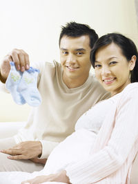 Happy expectant couple with baby socks at home