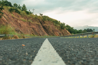 Surface level of road by mountain against sky