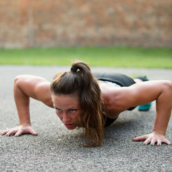 Mid adult woman doing push-ups on road