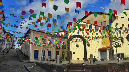 Multi colored flags hanging on street amidst buildings in city