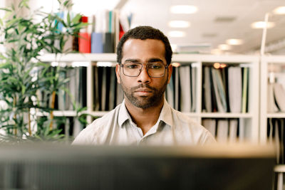 Male business professional wearing eyeglasses while working in office