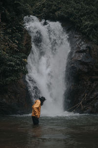 Mature man standing against waterfall