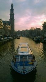 Boat sailing on river against sky during sunset