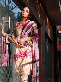 Portrait of young woman wearing dress by door