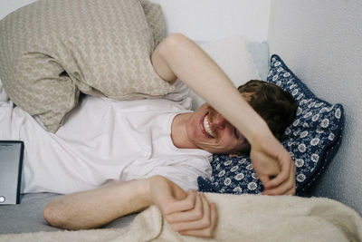 High angle view of happy man lying on bed at home