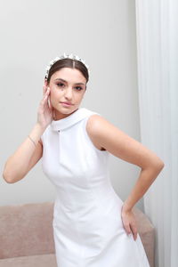 Indoor image of beautiful bride in white classic dress and bridal tiara, minimalist home interior