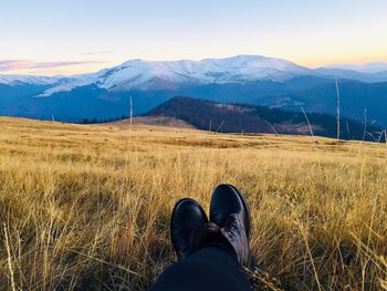 Low section of person standing on mountain against sky