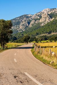 Road leading towards mountains against sky