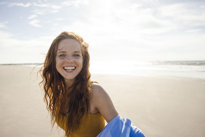 Portrait of a redheaded woman, laughing happily on the beach