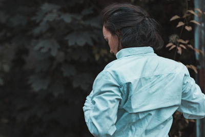 Rear view of woman standing outdoors against tree