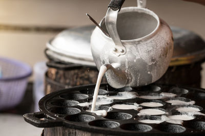 Close-up of pouring batter from kettle in container