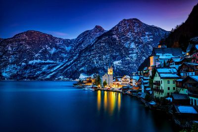 Scenic view of illuminated snowcapped mountains against sky at dusk