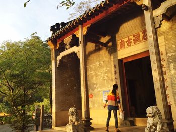Woman standing near entrance of old temple against sky