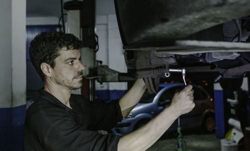 Side view mechanic using ratchet to adjust car brake disc detail while working in garage