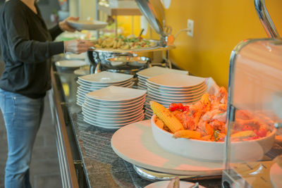 Midsection of woman serving food by table