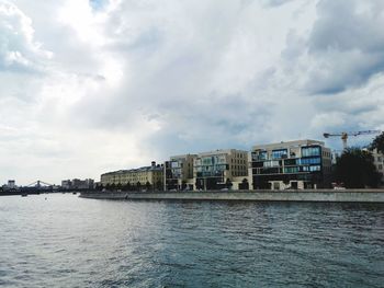 Scenic view of river by buildings against sky