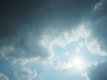 Low angle view of sunlight streaming through clouds