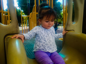 Cute girl sitting on slide in playground