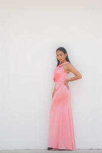 Full length of woman standing against pink background