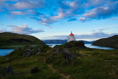 Lighthouse by sea against sky