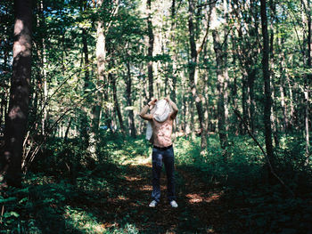 Full length of shirtless man standing in forest