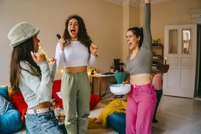 Young women shouting and cheering while watching tv at home