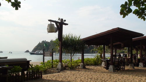 Chairs and tables at restaurant by sea against sky