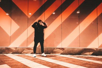 Full length of man photographing against wall