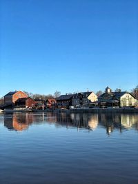 Buildings by lake against blue sky