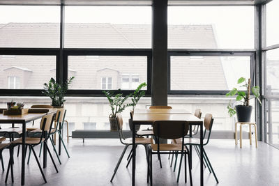 Empty desks and chairs by window at office