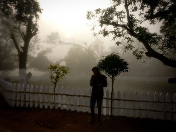 Silhouette man standing by railing against sky during rainy season